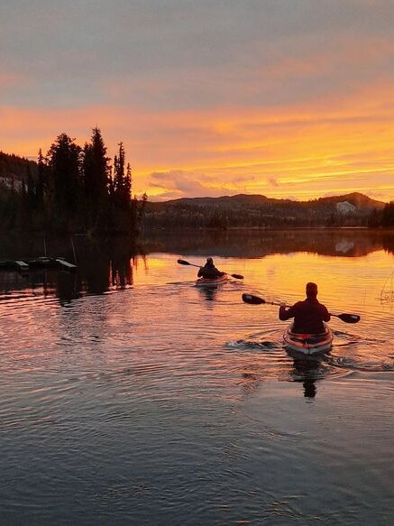 Two people kayaking on tranquil waters in Knouff Lake with a sunset scenery