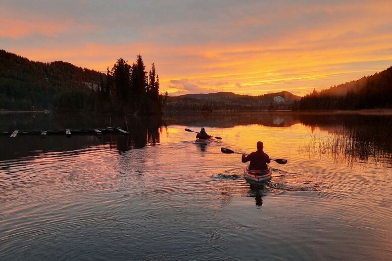 Two people kayaking on tranquil waters in Knouff Lake with a sunset scenery
