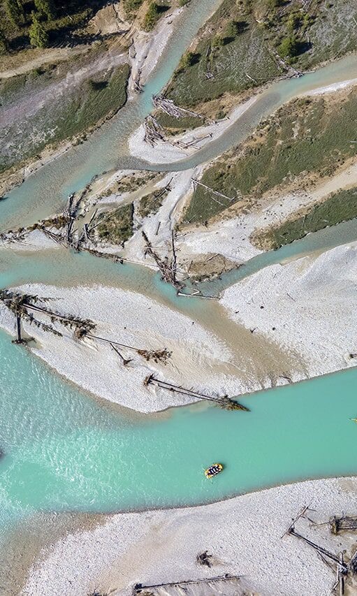 Aerial view of the Kicking Horse River, showcasing its turquoise waters, winding channels, and whitewater rafters navigating through the stunning landscape.