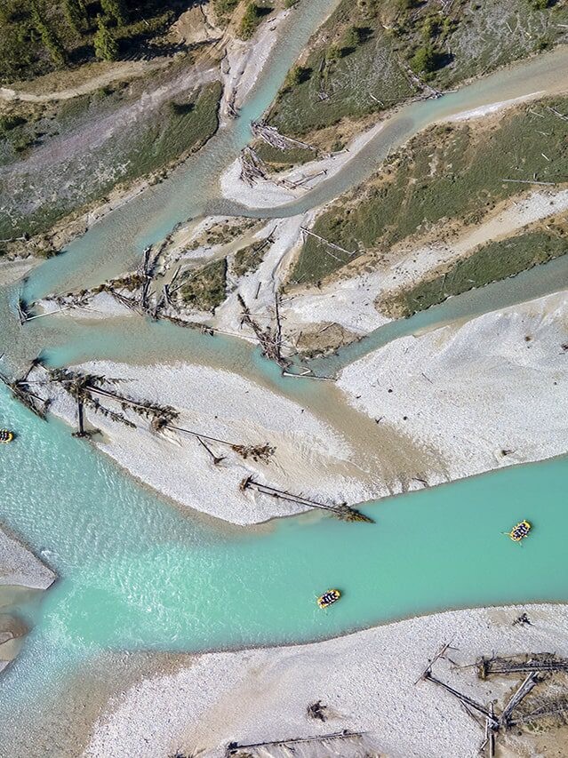 Aerial view of the Kicking Horse River, showcasing its turquoise waters, winding channels, and whitewater rafters navigating through the stunning landscape.