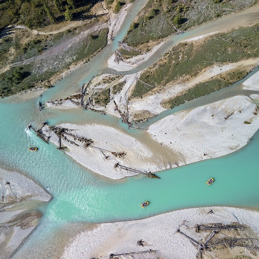 Aerial view of the Kicking Horse River, showcasing its turquoise waters, winding channels, and whitewater rafters navigating through the stunning landscape.